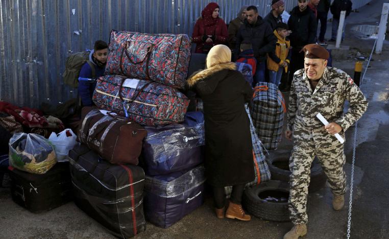 A member of the General Security Directorate, in charge of foreigners in Lebanon, passes by Syrian refugees waiting to board buses to take them home to Syria, in the northern Beirut suburb of Burj Hammoud, Lebanon, Thursday, Jan. 24, 2019.