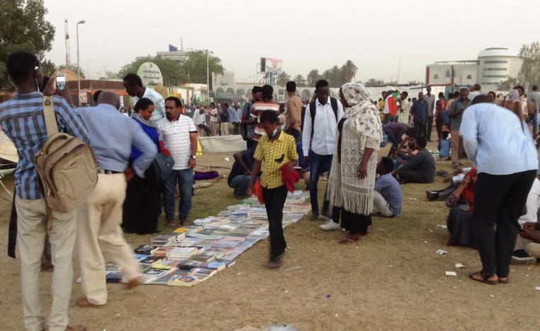 سودانيون يتجمعون حول كتب مفروشة على الارض