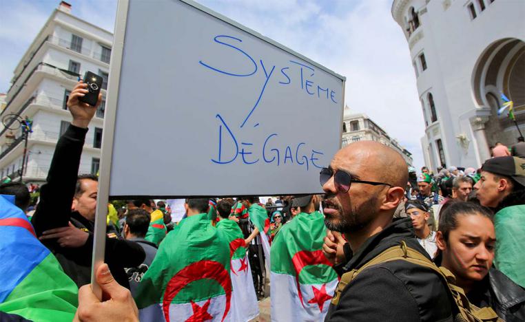 A man carries a sign reading "System, get out" during a protest seeking the departure of the ruling elite in Algiers