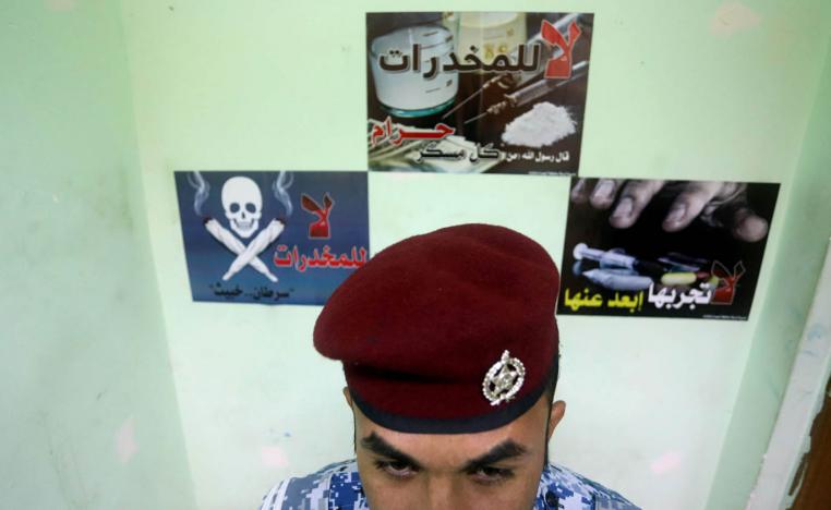 شرطي عراقي أمام ملصقات لمحاربة انتشار المخدرات في البصرة