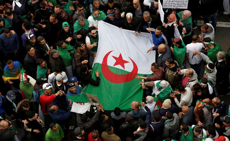 Demonstrators hold flags and banners as they return to the streets in Algiers