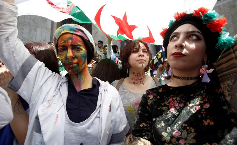 Demonstrators with painted faces hold flags during anti government protests in Algiers