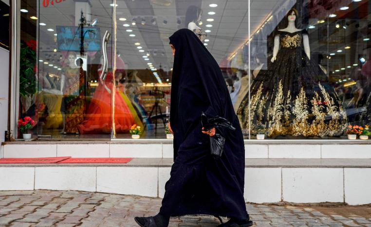 A woman walks past a dress shop in the central Iraqi city of Diwaniya on March 31, 2019