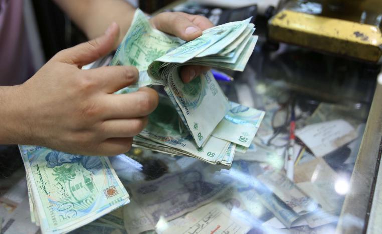 A shopkeeper counts money in his shop at a bazaar in Tunis