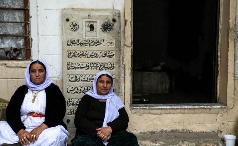 يزيديات يجلسن عند بوابة مقبرة في لاليش قرب دهوك في شمال العراق