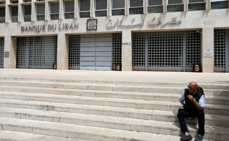 A man sits on the stairs in front of the central bank in Beirut