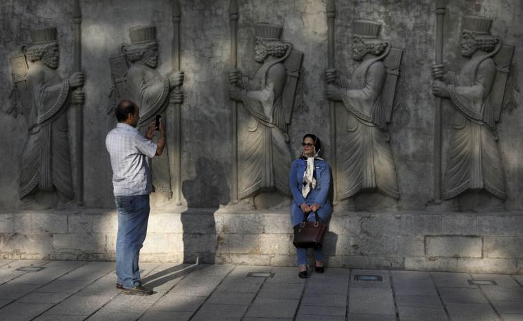 إيرانيان يلتقطان صورا بجانب مجسمات فارسية في طهران