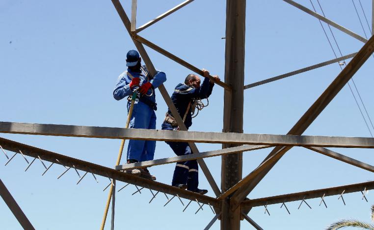 Workers operate on high voltage towers after they were damaged by fighting, south of Tripoli