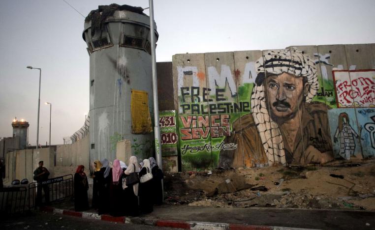 Palestinian women wait near a section of Israel's separation barrier