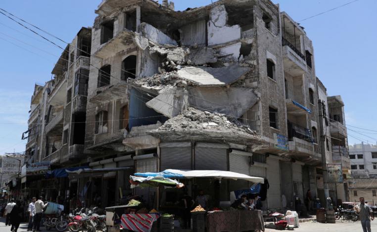 People walk past a damaged building in the city of Idlib