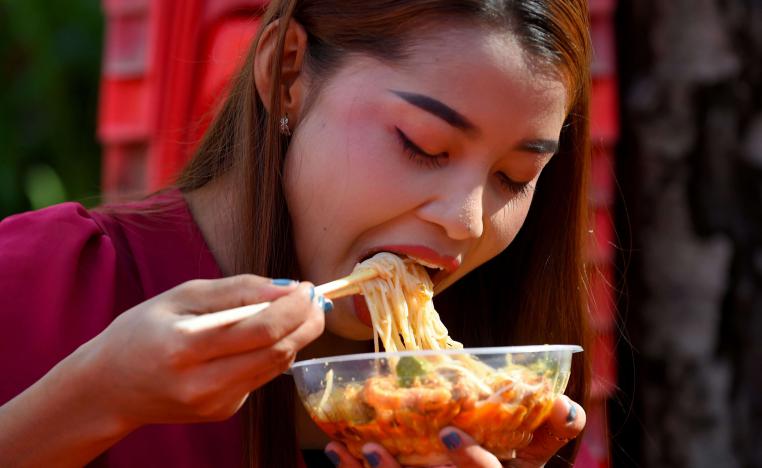فتاة تأكل المعكرونة في أحد مطاعم كمبوديا