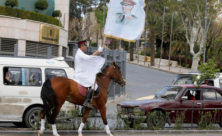 جندي سوري يرفع راية تحمل صورة الرئيس بشار الأسد وسط دمشق