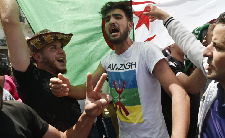 Algerian protesters shout anti-system slogans in front of a national flag during the weekly Friday demonstration in Algiers