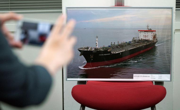 A journalist photographs a picture of the Kokuka Courageous, which was attacked near the Strait of Hormuz