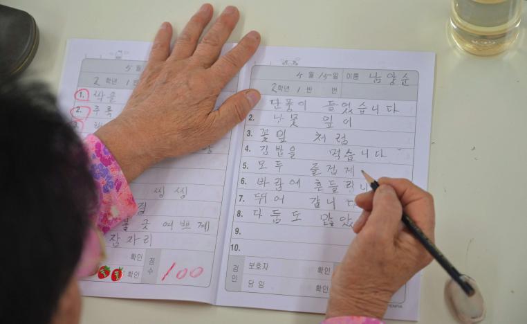 امرأة مسنة من كوريا الجنوبية تجري اختبارا إملائيا في إحدى المدارس