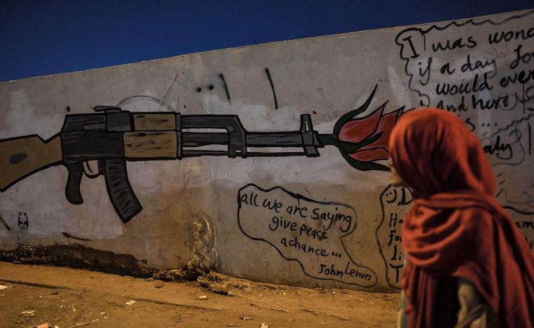 فتاة سودانية تنظر إلى جدارية تجسد بندقية في الخرطوم