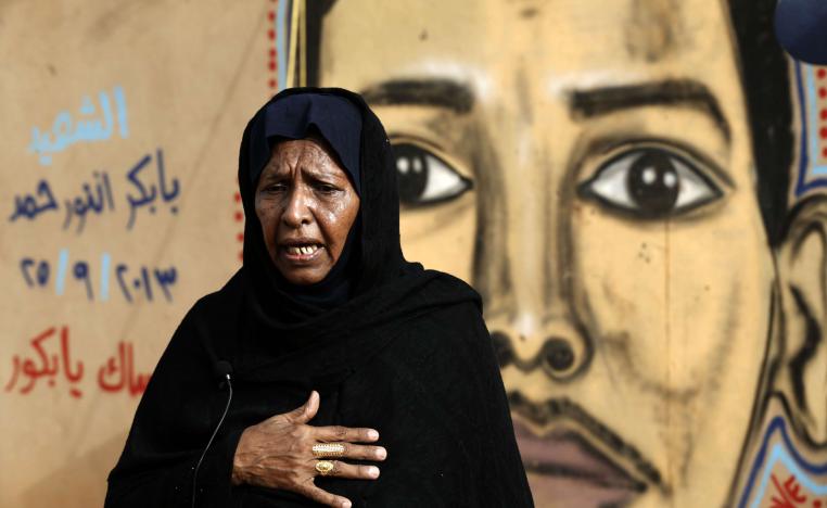 عدوية محمد والدة الشهيد بابكر أنور تقف أمام رسم يمثل ابنها على جدار في الخرطوم