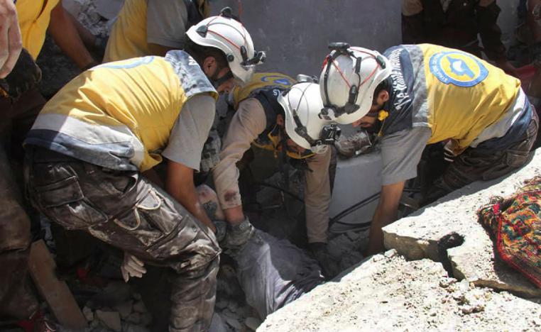 Syrian civil defense workers pull out a victim from under the rubble of a destroyed building