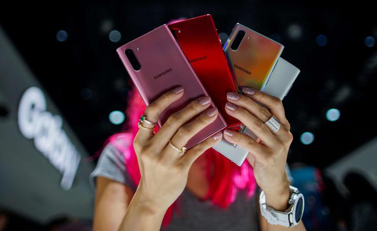 امرأة تحمل نماذج ملونة من هاتف غالاكسي نوت 10