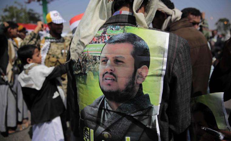 A Huthi supporter displays a poster of Abdel-Malek al-Houthi
