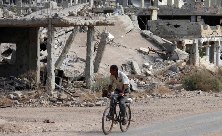 A Syrian man rides a bicycle past destroyed buildings in an opposition-held neighbourhood of the southern city of Daraa