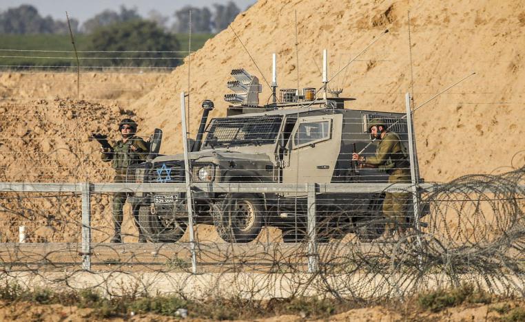  Israeli soldiers are seen next to a military vehicle across the barbed-wire fence with the Gaza Strip