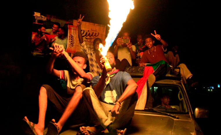 A man sets a gas canister on fire as Sudanese demonstraters celebrate in Khartoum