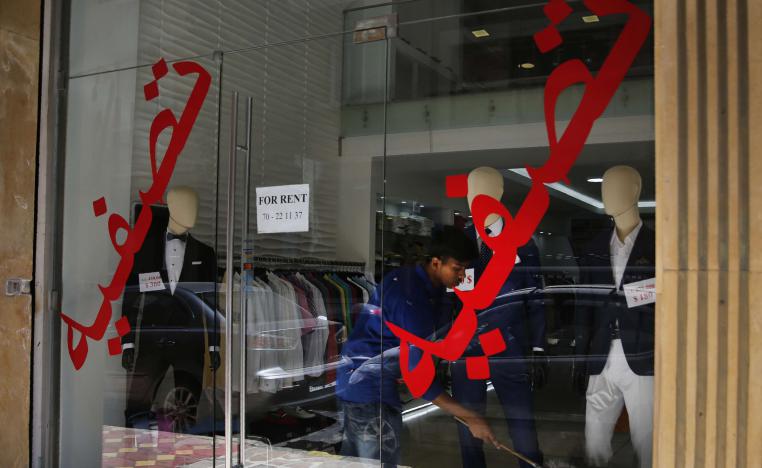A worker cleans a display in shop with Arabic on the window that reads "liquidation" in Beirut