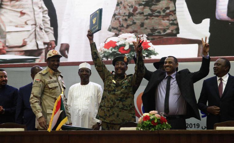 Sudan's protest leader Ahmad Rabie (2nd-R), flashes the victory gesture alongside General Abdel Fattah al-Burhan (C)