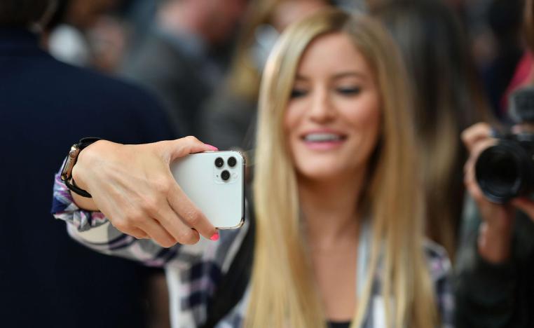 امرأة تستخدم آيفون 11 لأخذ صورة سيلفي