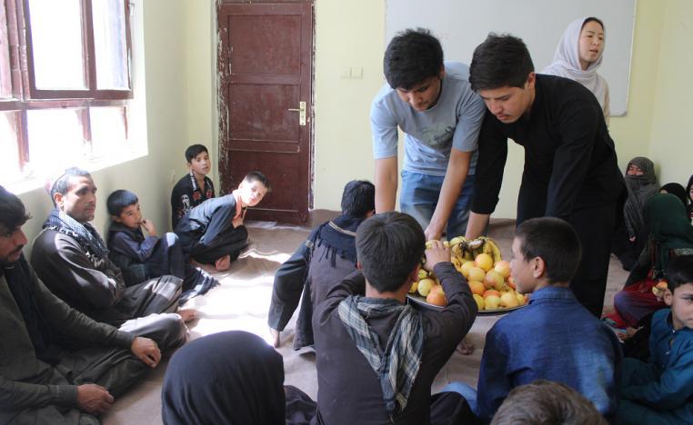 Habib (standing, left) serves fruit to parents at the Borderfree Street Kids School