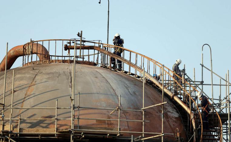 عمال يرممون خزانات في منشأة أرامكو التي تعرضت للهجوم