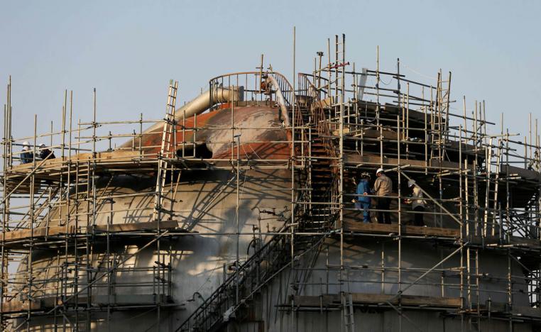 عمال يصلحون منشآت أرامكو التي تعرضت لهجوم بالصواريخ والطائرات المسيرة