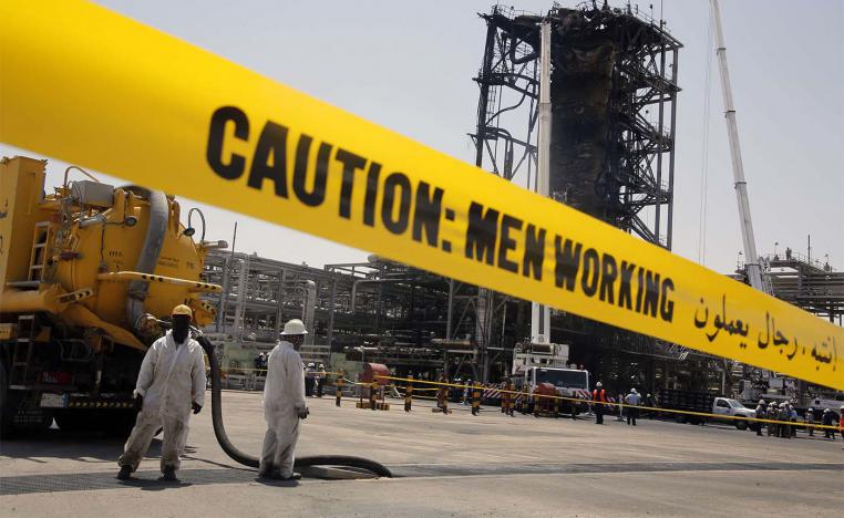Workers work in front of the recent attack Aramco's oil processing facility in Khurais