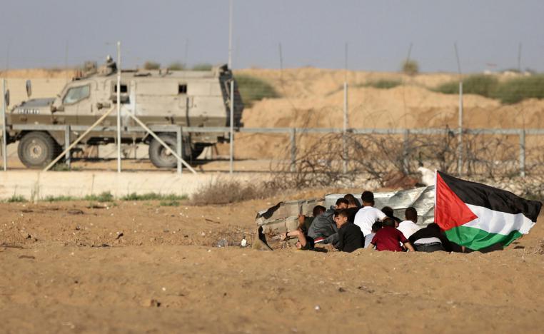 Palestinian protesters take cover during protests near the Gaza fence