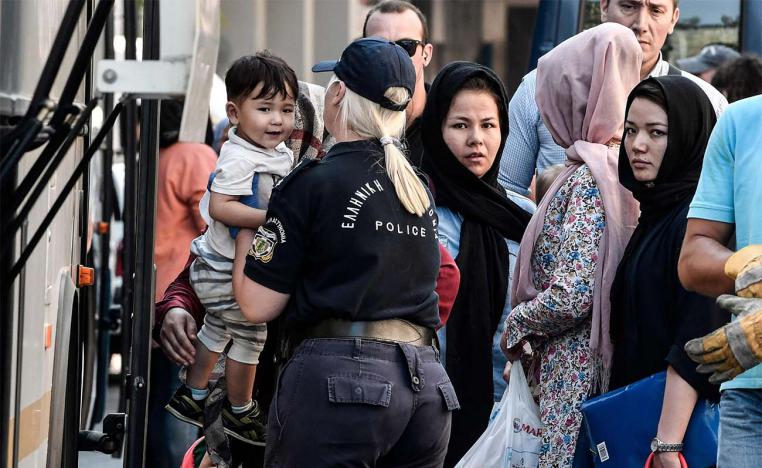 Evicted migrants board buses during a police operation in the center of Athens