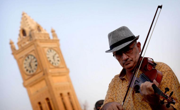 كردي يعزف على الكمان أمام برج قلعة كركوك