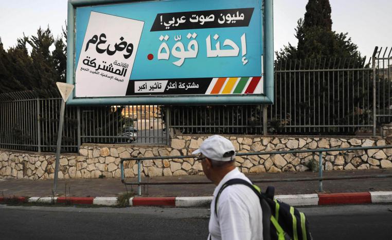 فلسطيني يمر بجانب اعلان للتصويت في الانتخابات الاسرائيلية