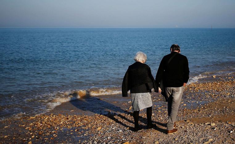 زوجان من كبار السن يمارسان رياضة المشي على الشاطئ