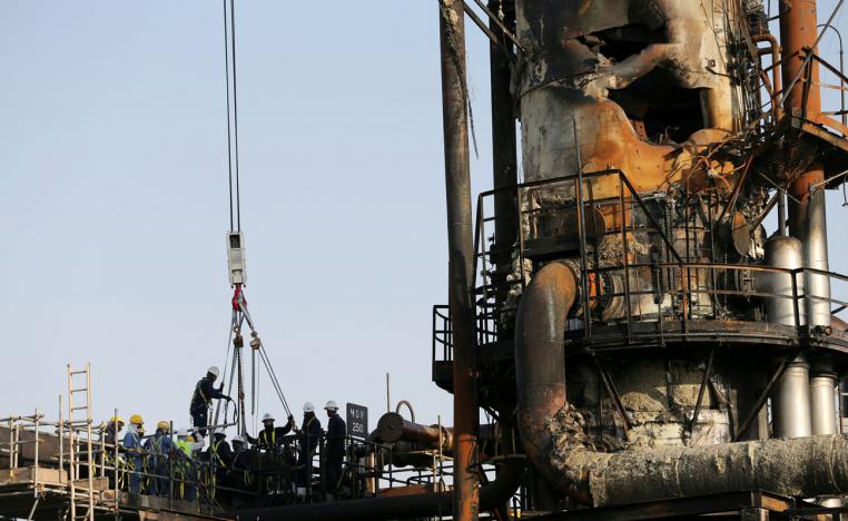 Workers are seen at the damaged site of Saudi Aramco oil facility in Abqaiq, Saudi Arabia