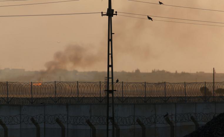 Barbed wire and smoke seen in a photo taken from the Turkish side of the border between Turkey and Syria