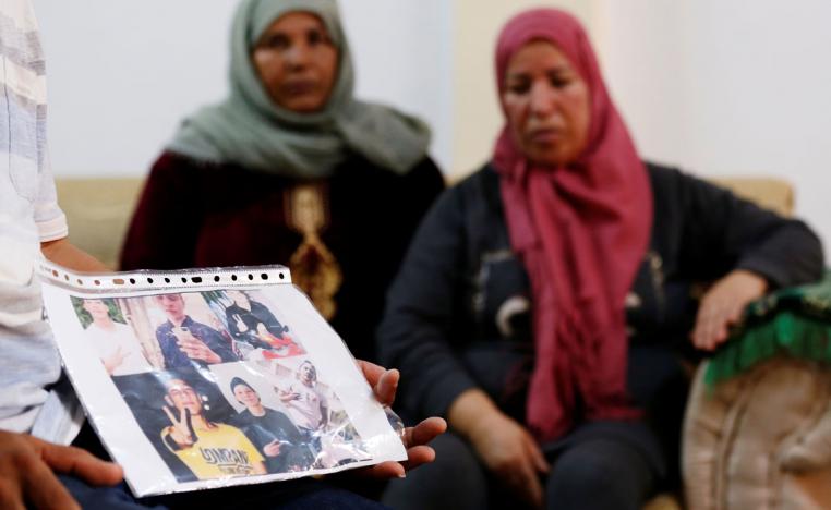 Mokhtar Hmidi, the father of Fakher who still unaccounted for after last week's capsizing off the Italian island of Lampedusa, shows pictures of his son, with Fakher's mother pictured in the background