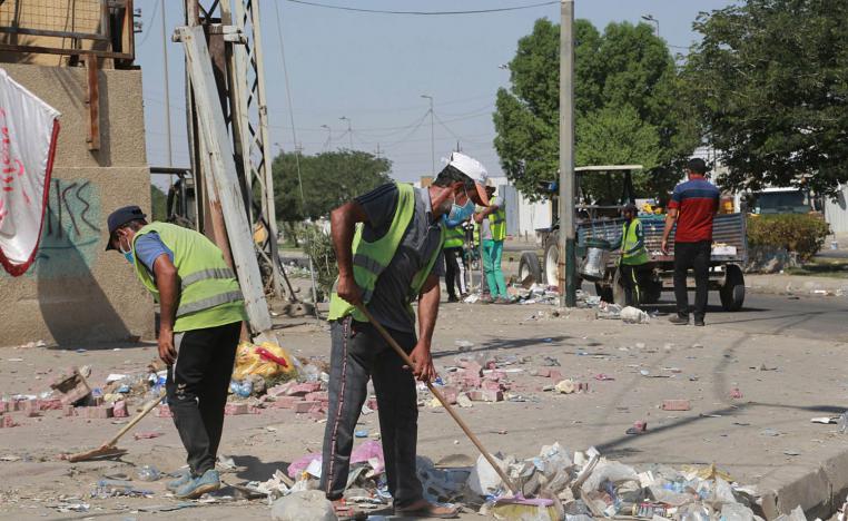 عمال بلدية يرفعون انقاضا بعد تظاهرة في بغداد