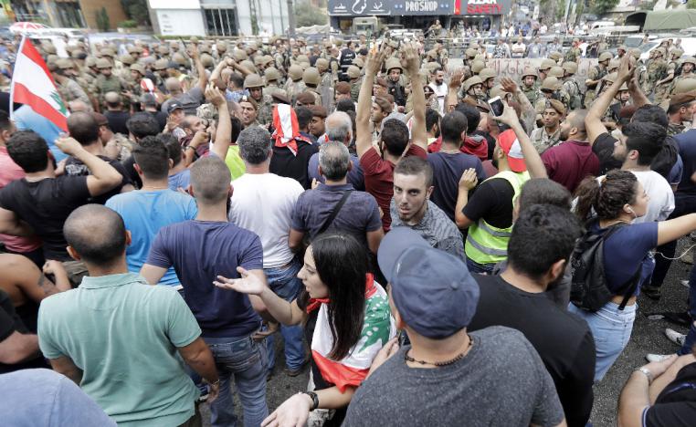 Lebanese protesters facing army soldiers yell slogans in the area of Zouk Mosbeh north of the capital Beirut