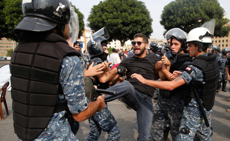 Police remove an anti-government protester blocking a main highway with his body in Beirut