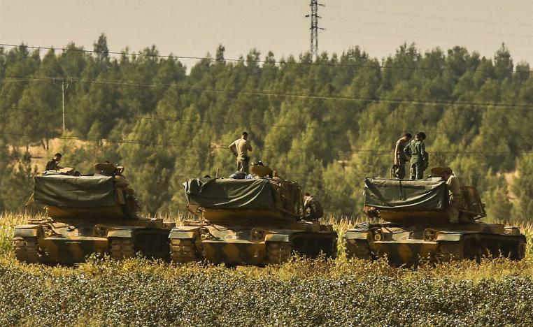 Turkish soldiers stand atop of their tanks at a staging area close to the border with Syria in Sanliurfa province, southeastern Turkey