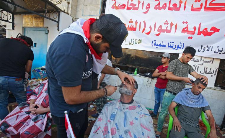 متظاهرون يحصلون حلاقة مجانية في ميدان التحرير ببغداد
