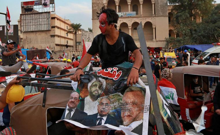 عراقي يضع صورة لسياسيين عراقيين محسوبين على إيران