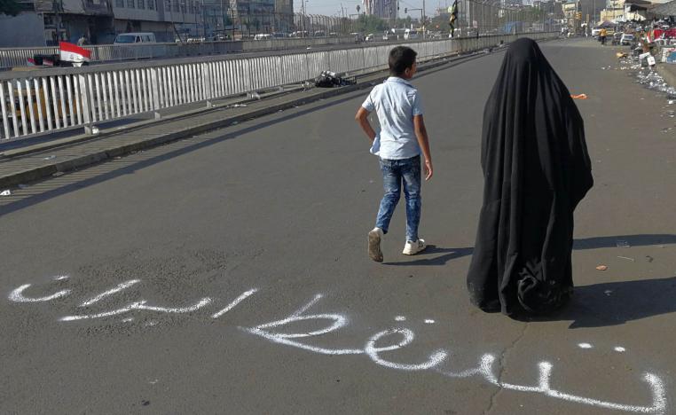 أم عراقية وابنها يمران في منطقة الاعتصامات في بغداد