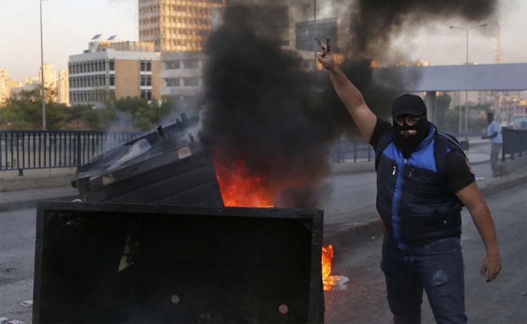 Anti-government protesters block a main highway by garbage containers in Beirut